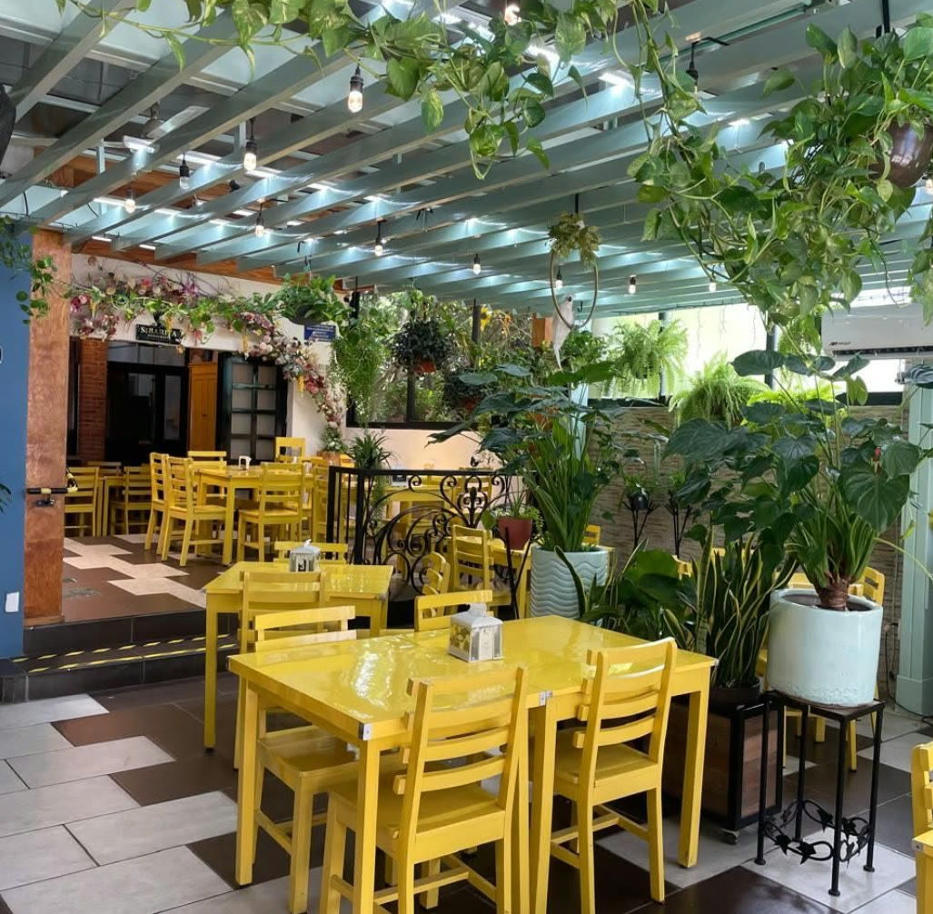 Interior de Sibarita Restaurante con mesas amarillas y pérgola de plantas, Tuxtla Gutiérrez